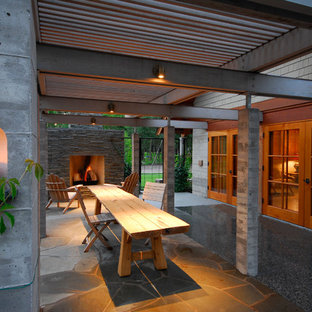 Idee per un ampio patio o portico minimalista dietro casa con un focolare, una pergola e graniglia di granito