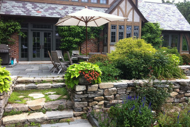 Exemple d'une grande terrasse arrière chic avec des pavés en pierre naturelle et aucune couverture.