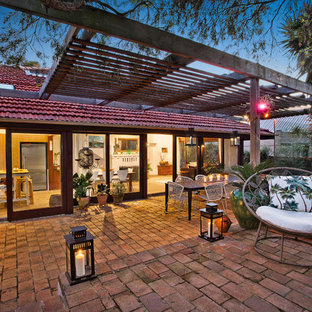 Immagine di un patio o portico contemporaneo di medie dimensioni e dietro casa con pavimentazioni in mattoni, fontane e una pergola