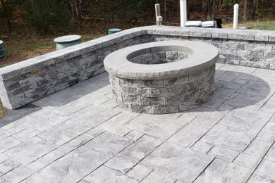 Large backyard stamped concrete patio photo in Other with a fire pit