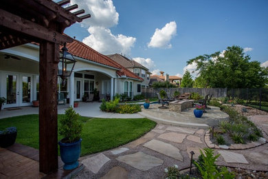 Diseño de patio tradicional grande en patio trasero con brasero, adoquines de piedra natural y pérgola