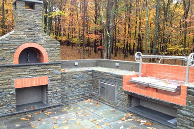 Large cottage backyard stone patio kitchen photo in New York with no cover