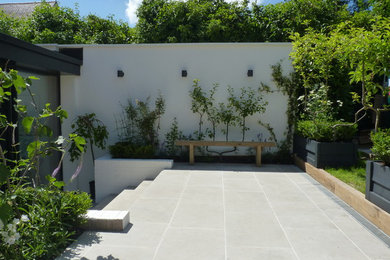 Large contemporary back patio in Berkshire with natural stone paving and no cover.