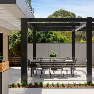This is an example of a mid-sized contemporary backyard patio in Melbourne with tile and a pergola.