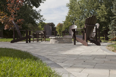 Example of a large classic backyard concrete paver patio design in Other with a fire pit and no cover