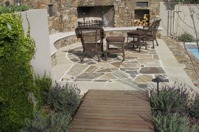 Example of a mid-sized mountain style backyard stone patio design in Orange County with a fire pit and no cover