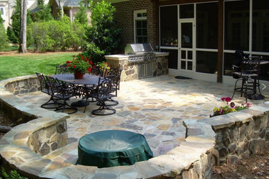 Imagen de patio clásico grande sin cubierta en patio trasero con cocina exterior y adoquines de piedra natural