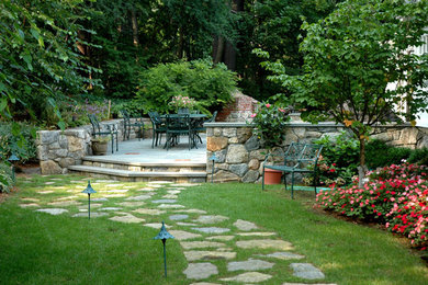 Example of a large classic backyard stone patio kitchen design in New York with no cover