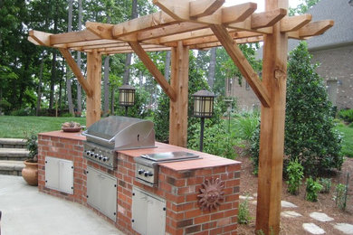 Inspiration for a large transitional backyard concrete paver patio kitchen remodel in Charlotte with a pergola