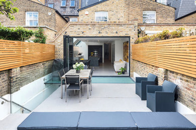 Contemporary back patio steps in London with concrete slabs and no cover.