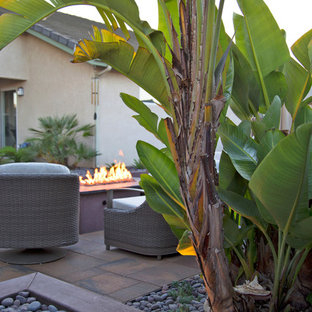 Idee per un piccolo patio o portico tropicale dietro casa con un focolare e pavimentazioni in cemento