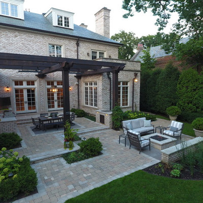 Inspiration for a large timeless backyard stone patio kitchen remodel in Chicago with a pergola