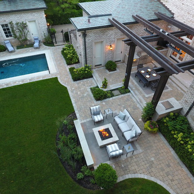 Inspiration for a large timeless backyard stone patio kitchen remodel in Chicago with a pergola