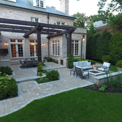 Patio kitchen - large traditional backyard stone patio kitchen idea in Chicago with a pergola