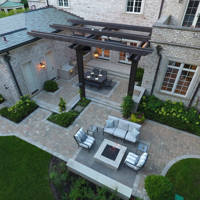 Patio kitchen - large traditional backyard stone patio kitchen idea in Chicago with a pergola