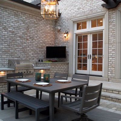 Large elegant backyard stone patio kitchen photo in Chicago with a pergola