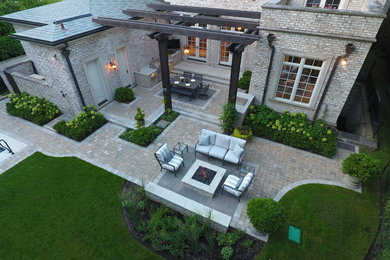 Example of a large classic backyard stone patio kitchen design in Chicago with a pergola