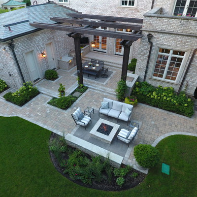 Example of a large classic backyard stone patio kitchen design in Chicago with a pergola