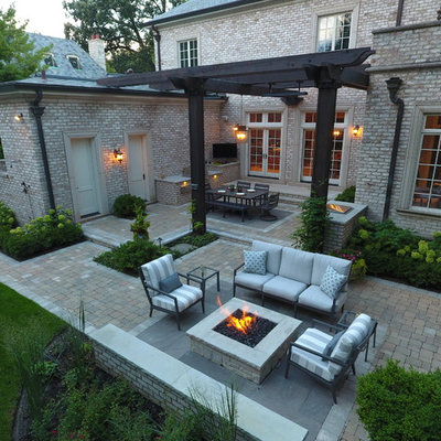 Large elegant backyard stone patio kitchen photo in Chicago with a pergola