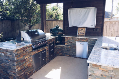 Patio kitchen - large backyard stamped concrete patio kitchen idea in Houston with a pergola