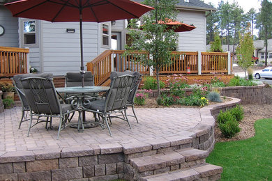 Example of a mid-sized classic backyard brick patio design in Phoenix with a fire pit and no cover