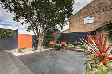 Small contemporary back patio in Other with natural stone paving.