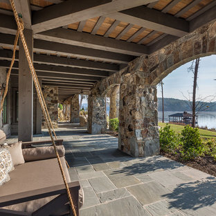 Immagine di un ampio patio o portico stile rurale dietro casa con piastrelle e un tetto a sbalzo