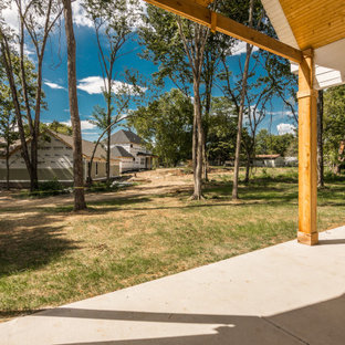 Esempio di un patio o portico country di medie dimensioni e dietro casa con un caminetto, lastre di cemento e un tetto a sbalzo