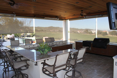 Exemple d'une grande terrasse arrière chic avec une cuisine d'été, du carrelage et une pergola.
