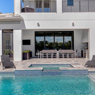 Ispirazione per un grande patio o portico moderno dietro casa con piastrelle e un tetto a sbalzo