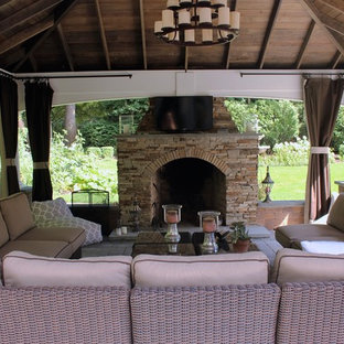 Ispirazione per un patio o portico classico di medie dimensioni e dietro casa con un focolare, pavimentazioni in cemento e un gazebo o capanno