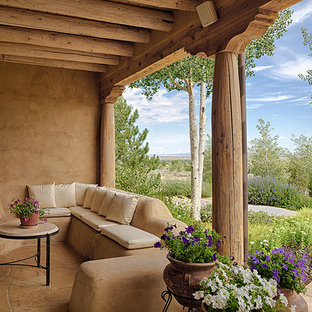 Immagine di un patio o portico stile americano di medie dimensioni e dietro casa con un focolare, pavimentazioni in pietra naturale e un tetto a sbalzo