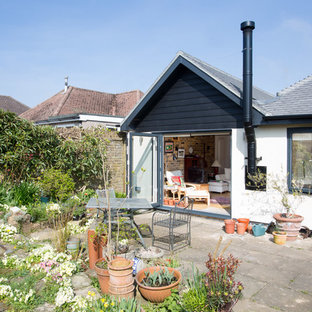Design ideas for a farmhouse back patio in Surrey with concrete paving and no cover.