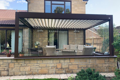 Design ideas for a large modern back patio in Dorset with concrete paving and a pergola.