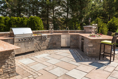 Idée de décoration pour une terrasse arrière tradition de taille moyenne avec une cuisine d'été, des pavés en pierre naturelle et aucune couverture.