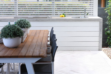 Cette image montre une petite terrasse arrière design avec une cuisine d'été, du carrelage et une extension de toiture.
