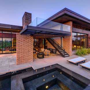 Esempio di un grande patio o portico moderno dietro casa con un focolare, piastrelle e un tetto a sbalzo