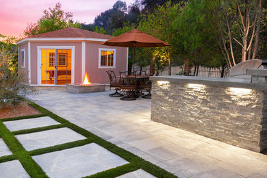 Photo of a back patio in Los Angeles with a fire feature and natural stone paving.