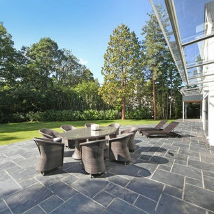 This is an example of an expansive contemporary back patio in Other with an awning.