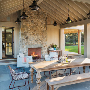 Immagine di un patio o portico country con un caminetto e un tetto a sbalzo