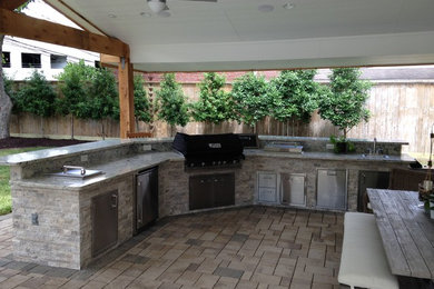 Patio kitchen - large traditional backyard stone patio kitchen idea in Houston with a roof extension