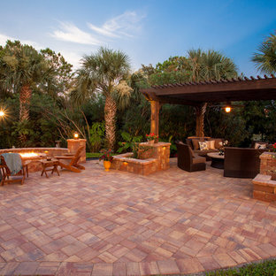 Esempio di un ampio patio o portico tradizionale dietro casa con un focolare, pavimentazioni in pietra naturale e una pergola