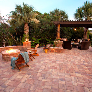 Foto di un ampio patio o portico chic dietro casa con un focolare, pavimentazioni in pietra naturale e una pergola