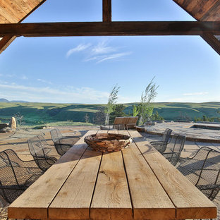Idee per un grande patio o portico stile rurale dietro casa con un focolare, pavimentazioni in pietra naturale e un tetto a sbalzo