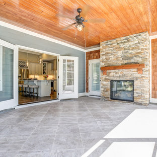 Foto di un grande patio o portico stile americano dietro casa con piastrelle e un tetto a sbalzo