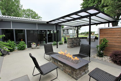 Inspiration for a mid-sized modern stamped concrete patio remodel in Other with a fire pit and an awning
