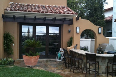 Ejemplo de patio mediterráneo de tamaño medio en patio trasero con cocina exterior, adoquines de piedra natural y pérgola