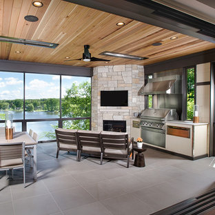 Immagine di un patio o portico design con piastrelle e un tetto a sbalzo