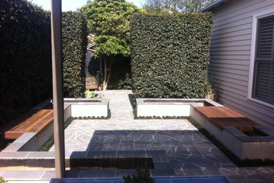 Ejemplo de patio contemporáneo de tamaño medio sin cubierta en patio trasero con adoquines de piedra natural