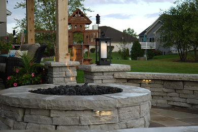 Example of a mid-sized classic backyard stone patio design in Other with a fire pit and a pergola